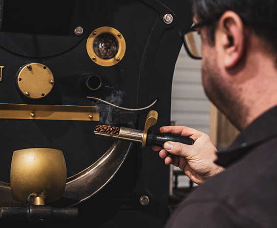 Foto von Mitarbeiter, der den Röststand des Kaffees überprüft